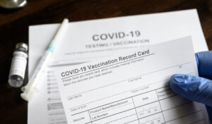 COVID-19 Vaccination Record Card in doctor's hand.