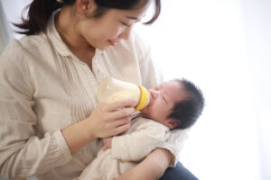 Asian mother feeding her infant with a bottle of formula.